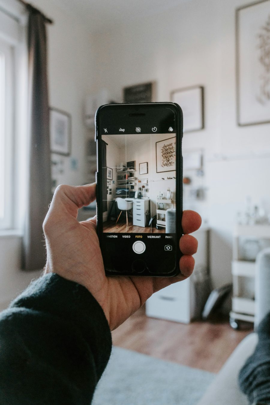 A parent holding up a phone to photograph a tidy home workspace